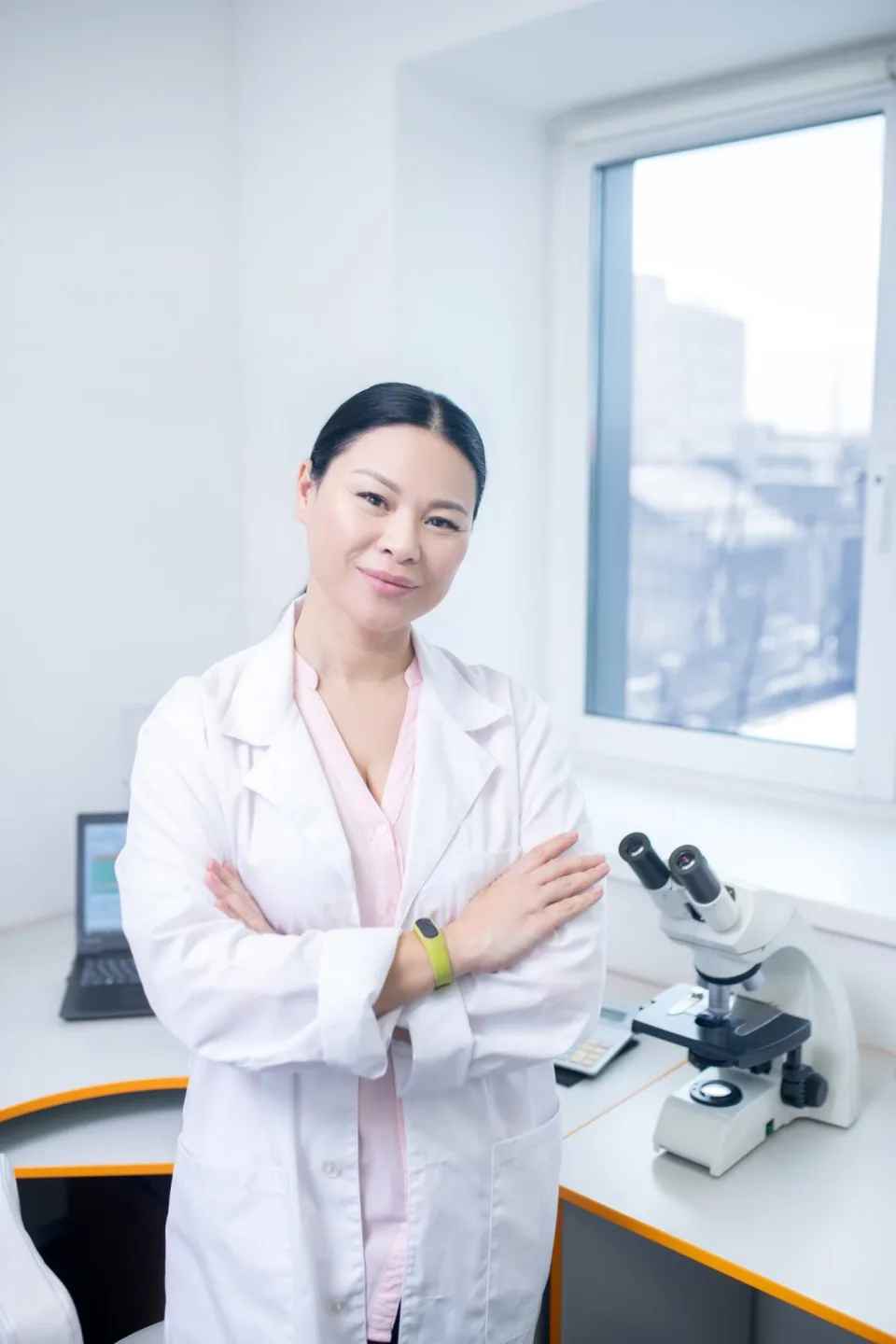 Scientist in a white lab coat standing by a bright laboratory window